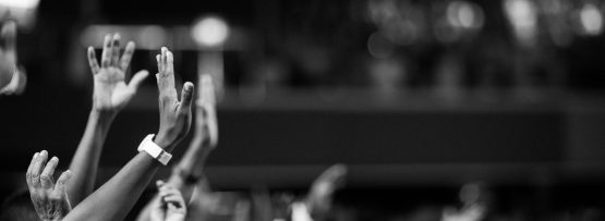 Black and white image of audience with hands raised, capturing concert energy.